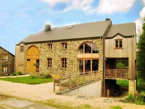 Ein Steinhaus mit Holztür, Fenstern und einem Balkon.