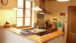 A kitchen with wooden beams, a window, a stove, and hanging kitchen utensils. - Fort-like Holiday Home in Sart-bertrix, Near Luxembourg (Bertrix)