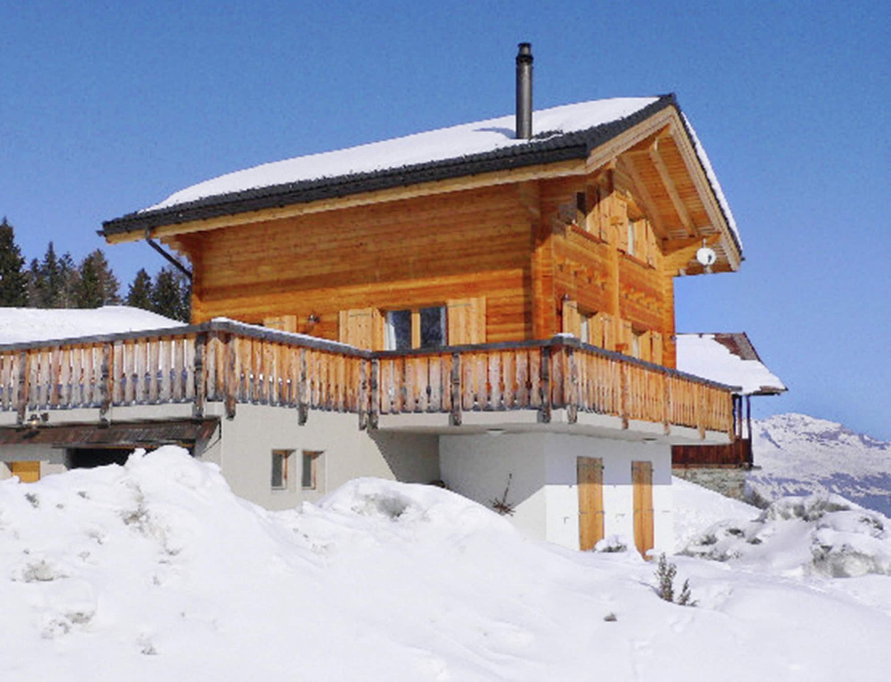 A wooden chalet with a balcony, surrounded by snow.
