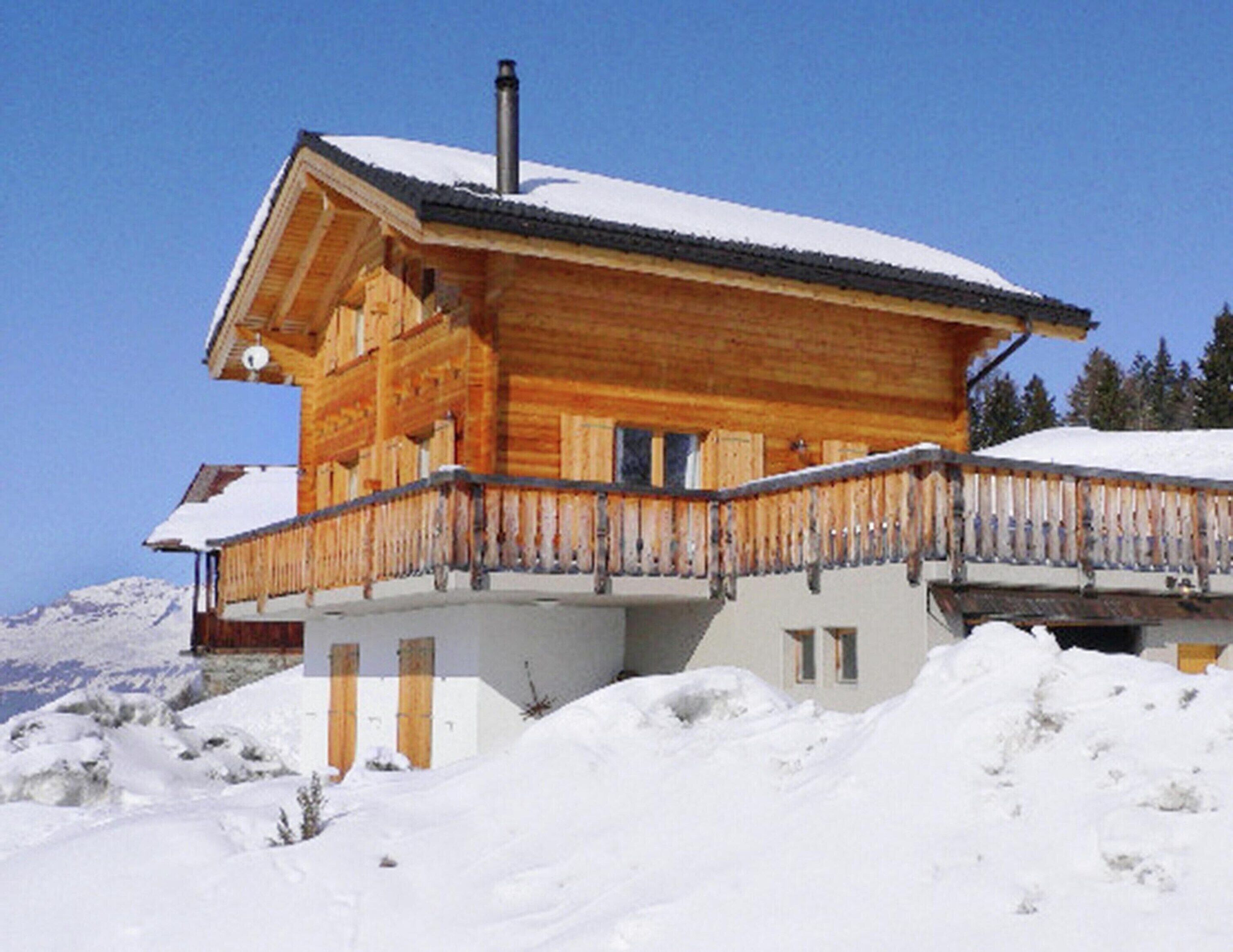 A wooden chalet with a balcony, surrounded by snow.