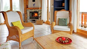 Ein gemütliches Zimmer mit Korbstühlen, einem Holztisch, einem Kamin und einem Bücherregal.