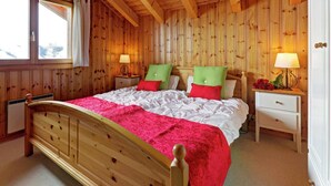 Ein Schlafzimmer mit Holzwänden, einem Bett, zwei Nachttischen und einem Fenster.