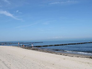 A beach with a clear sky, calm sea, and wooden piers. - Ferienhaus Ostseeblick in Kuhlungsborn (Kuehlungsborn)