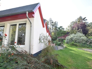 A house with a red and white exterior, a visible window, and a garden with various plants and a pathway. - Holiday Home in Khlungsborn With Garden (Kuehlungsborn)