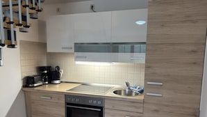 A modern kitchen with a dishwasher, a coffee maker, and a sink. - Graal-muritz Garden Balcony Stay (Graal Mueritz)