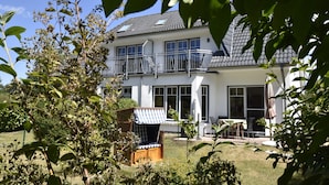 A two-story house with a balcony, a garden with a chair, and a table. - Graal-muritz Garden Balcony Stay (Graal Mueritz)