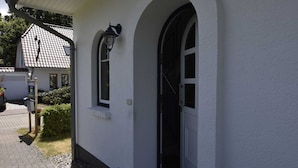 A building with a white exterior, a black door, and a window with a light fixture. - Graal-muritz Garden Balcony Stay (Graal Mueritz)