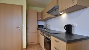 A compact kitchen with wooden cabinets, a microwave, a kettle, and a coffee maker. - Spacious Holiday Home in Zierow near Sea (Zierow)