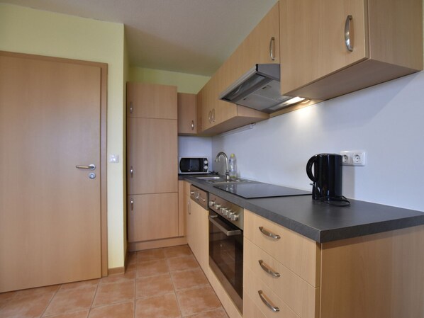 A compact kitchen with wooden cabinets, a microwave, a kettle, and a coffee maker. - Spacious Holiday Home in Zierow near Sea (Zierow)