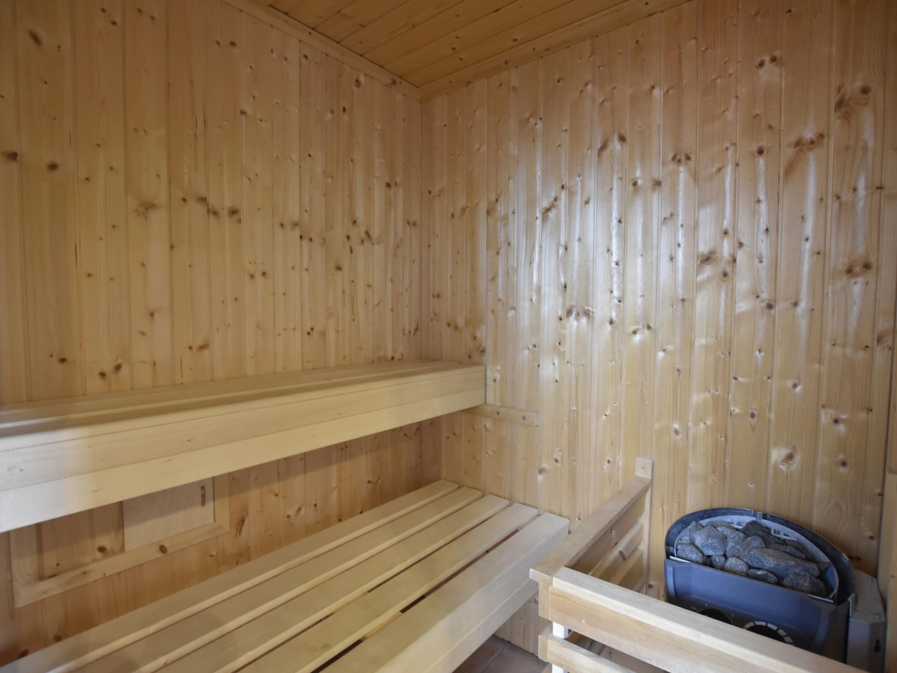 A sauna with wooden benches and a stone-filled basin.