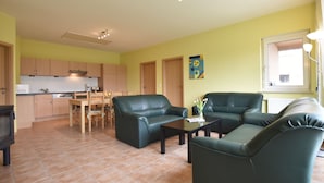A living room with a dining area, kitchen, and a window with curtains. - Komfortables Wohnung in Zierow mit Sauna (Zierow)