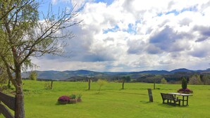 A grassy field with a wooden bench and a table, surrounded by a wooden fence and trees. - Wohnung in Silbecke mit Garten (Attendorn)