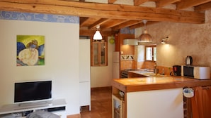 A kitchen with wooden beams, a television, a painting, and a sink. - Holiday Home in Ardeche With Pool (Saint Alban Auriolles)