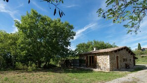 A stone house with a tiled roof, surrounded by trees and a gravel path. - Holiday Home in Ardeche With Pool (Saint Alban Auriolles)
