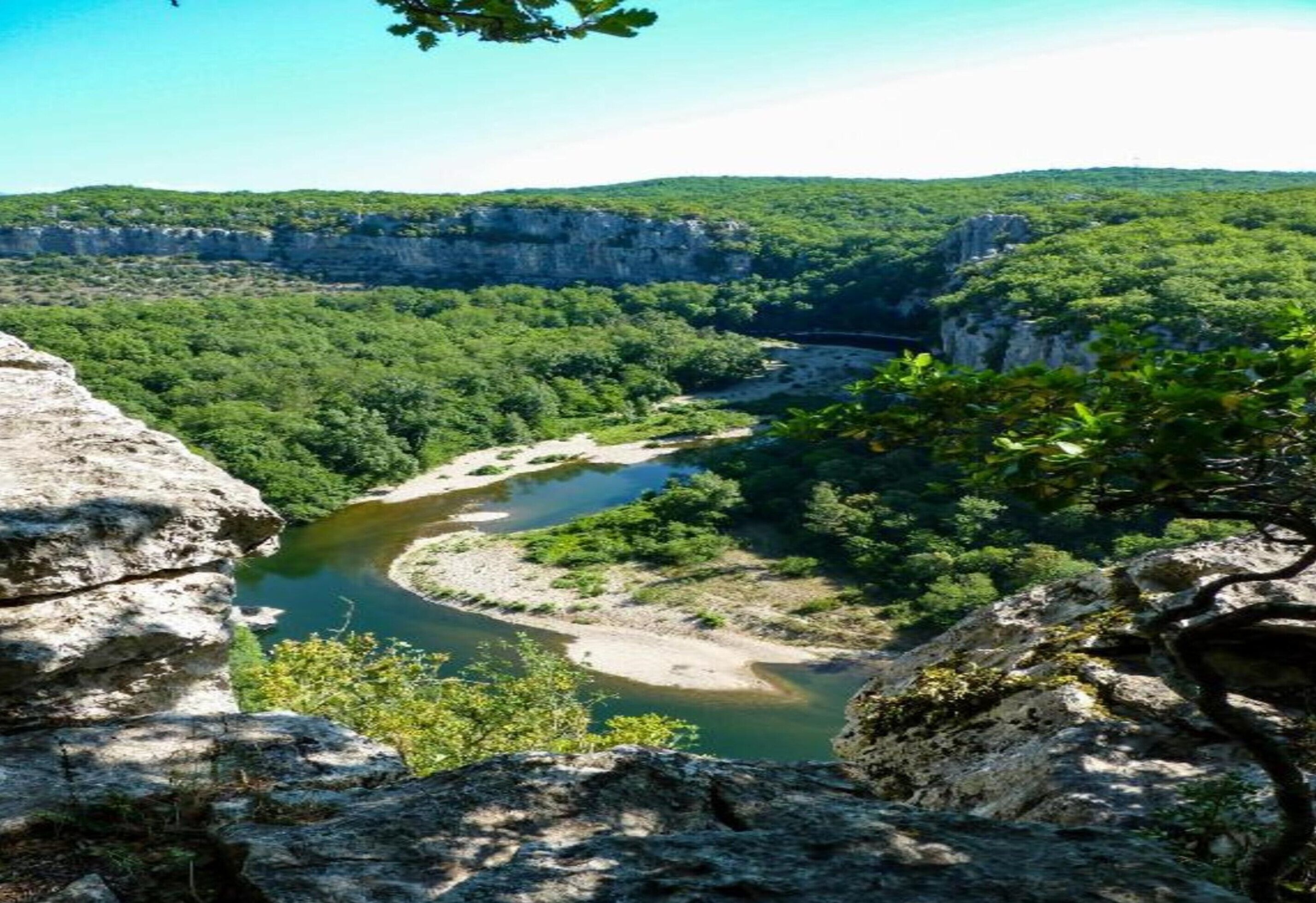 A river winding through a forested valley with rocky cliffs on one side.