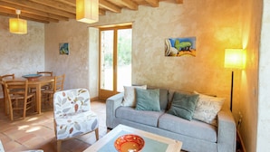A cozy living room with a sofa, a dining table with chairs, and a painting on the wall. - Holiday Home in Ardeche With Pool (Saint Alban Auriolles)