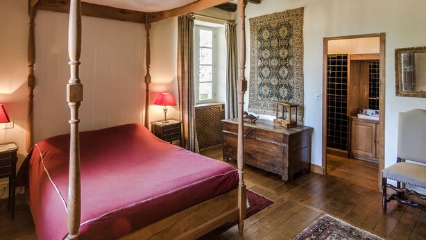 A four-poster bed with a red bedspread, wooden furniture, and a patterned tapestry on the wall. - Mansion in Sourzac With Private Pool (Sourzac)