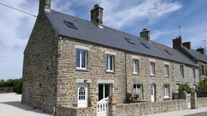 A stone building with a gabled roof, multiple windows, and a white door. - Quiet Normandy Retreat (La Haye)