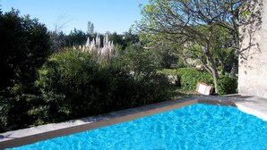 A swimming pool with clear blue water, surrounded by lush greenery and a tree. - Holiday Home in Provence With Private Pool (Cavaillon)