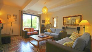 A living room with a sofa, armchair, and coffee table, a large window with curtains, and a chandelier. - Holiday Home in Provence With Private Pool (Cavaillon)
