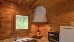 Interior de uma cabana de madeira com cozinha, incluindo pia, fogão e micro-ondas.
