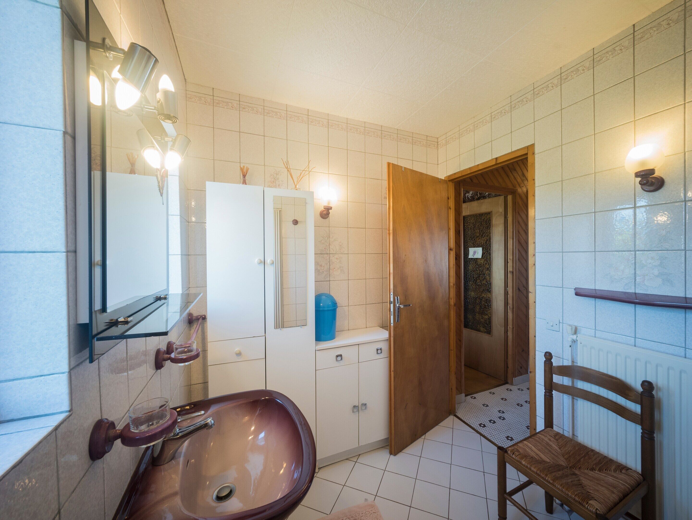 A bathroom with a sink, mirror, and wooden door.