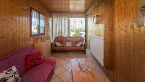 Ein Holzinterieur mit einem roten Sofa, einem braunen Ledersofa und einem Holztisch.