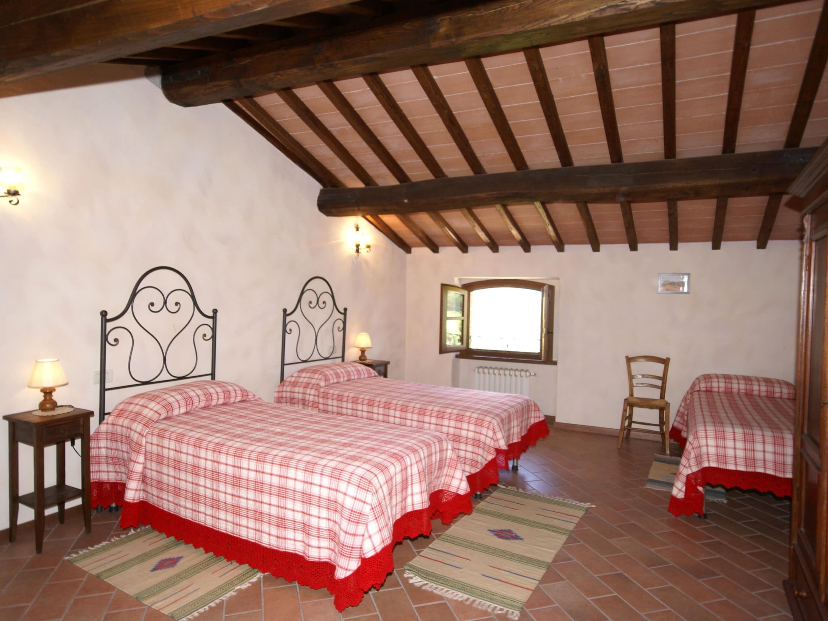 Ein Schlafzimmer mit zwei Betten, Holzbalken, einem Fenster und einer Heizung.