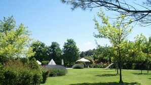 Um jardim bem cuidado com gramado, algumas árvores e um gazebo.