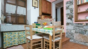 Uma cozinha com armários de madeira, uma mesa com toalha de mesa florida e uma parede de pedra.