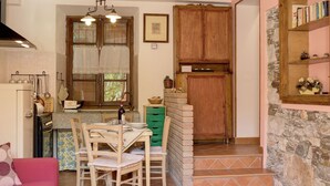 Cozinha acolhedora com mesa de jantar, cadeiras e um sofá vermelho.