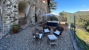 Eine Außenpatio mit Steinmauern, einem Whirlpool, Korbmöbeln und Blick auf die Hügel.