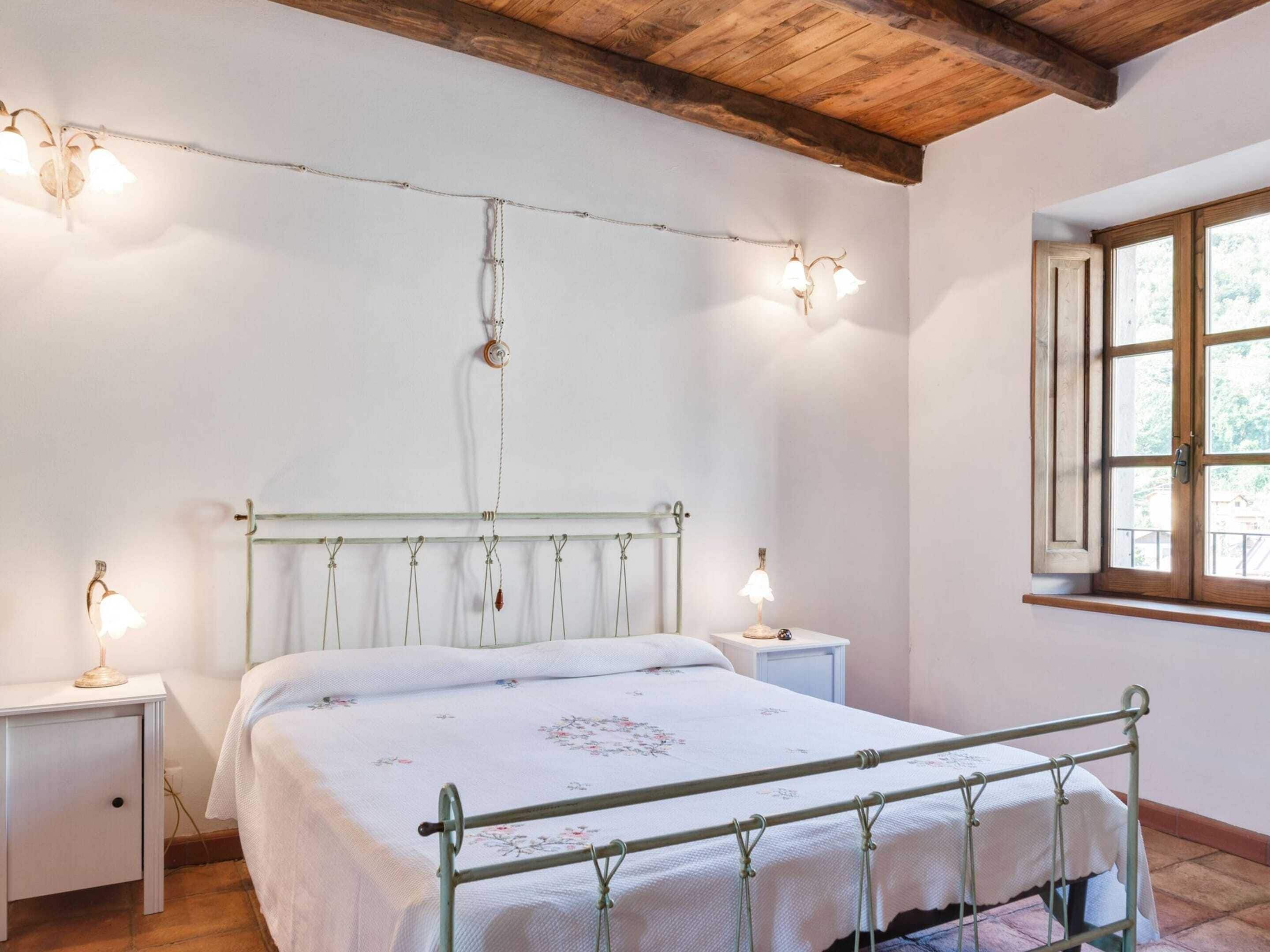 A bedroom with a metal bed frame, a wooden ceiling, and a window with a view.