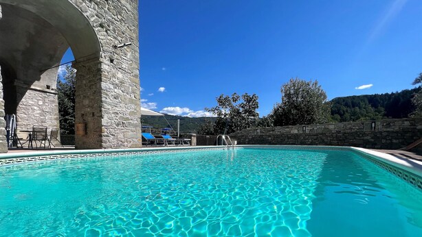 Ein klarer, blauer Pool mit Steinmauern und einem steinernen Bogen.