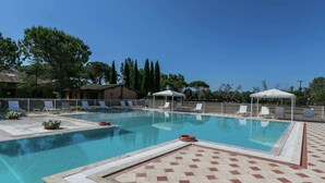 A swimming pool with lounge chairs and a lifebuoy, surrounded by a fence and trees. - Apartment Near the Beach and the Clear Blue Sea (Grosseto)