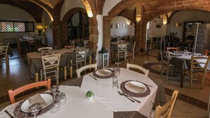 A restaurant with brick arches, white tablecloths, and wooden chairs. - Apartment Near the Beach and the Clear Blue Sea (Grosseto)