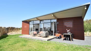 Ein modernes Haus mit Terrasse, ausgestattet mit Gartenmöbeln und einem Tisch.