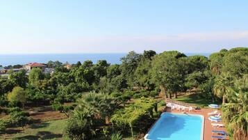 Relax by the resort's large pool surrounded by lush greenery and palm trees.