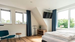 A bedroom with a bed, a desk, a chair, and a TV mounted on the wall. - Holiday Home in Texel Near the Sea (De Koog)