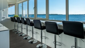 A modern kitchen with a long counter and black bar stools, large windows with a view of the sea. - Apartment in Kamperland by Veerse Meer Lake (Kamperland)
