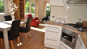 Une cuisine moderne dotée d’un four encastré, un coin repas avec une table et des chaises, et une vue sur l’extérieur.
