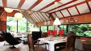 A dining area with a wooden table set for four, surrounded by wooden chairs, under a sloped ceiling with exposed beams. - Spacious Holiday Home in Eersel With Open Fire (Eersel)