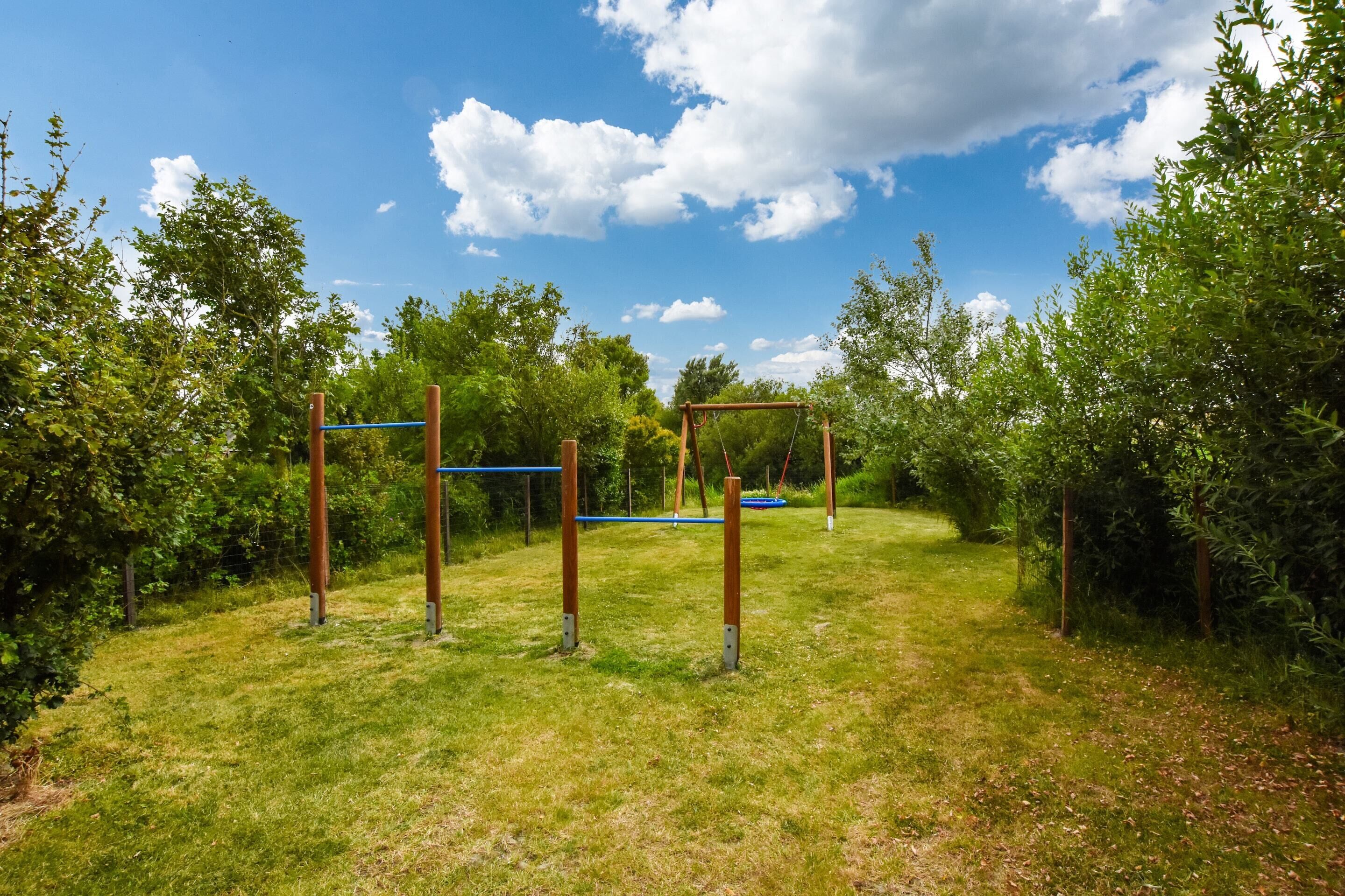 An outdoor area with exercise equipment, surrounded by greenery and trees.