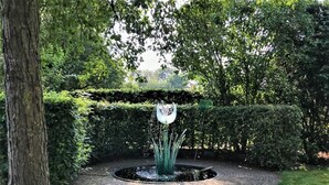 A circular brick pathway with a central water feature surrounded by well-maintained hedges and trees. - Apartment Noordwolde Rural Retreat (Noordwolde)
