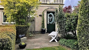 A house with a green door, a balcony, and a garden with a bench. - Apartment Noordwolde Rural Retreat (Noordwolde)