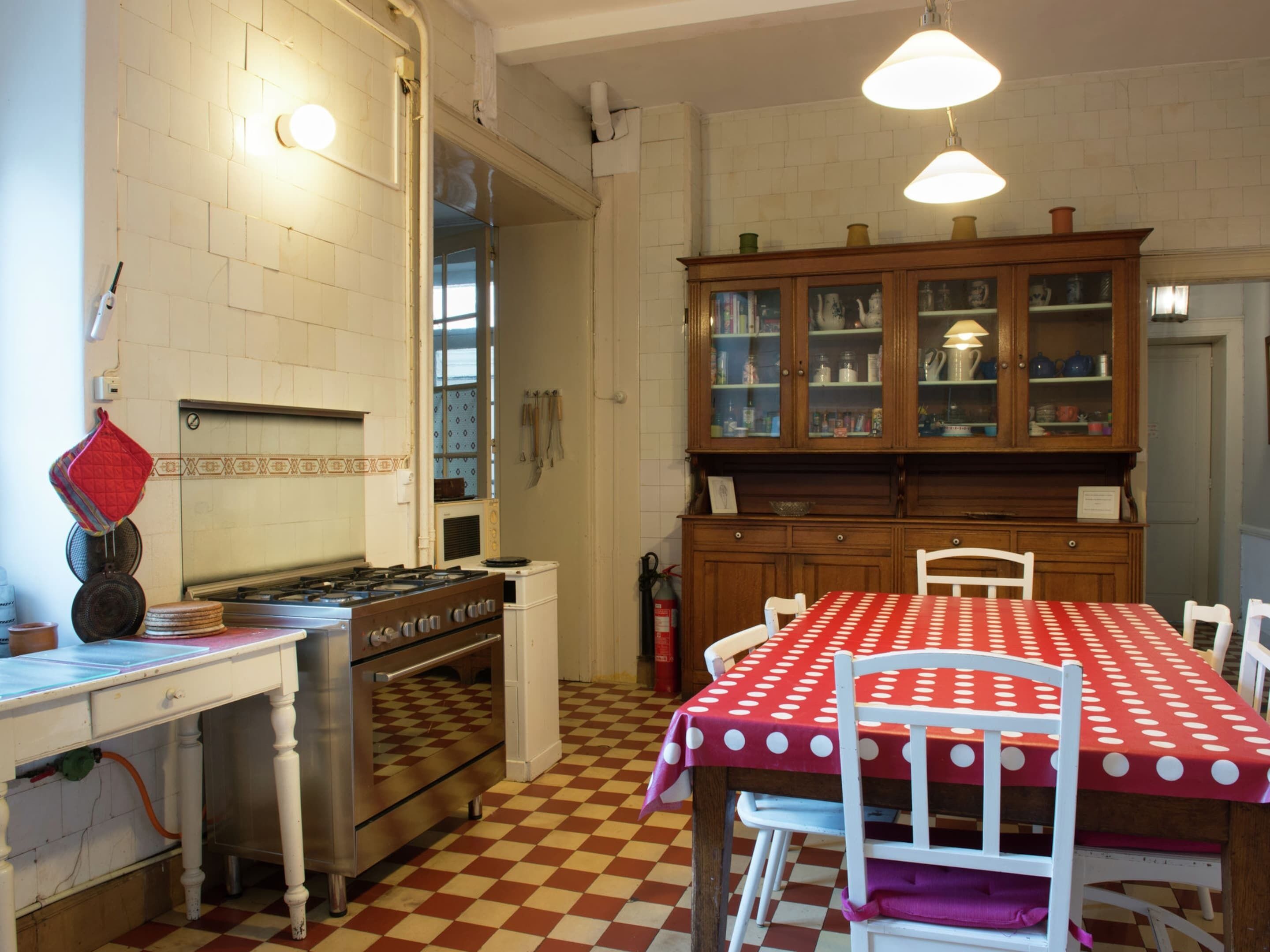 Een keuken met een fornuis, oven en eettafel met stoelen.