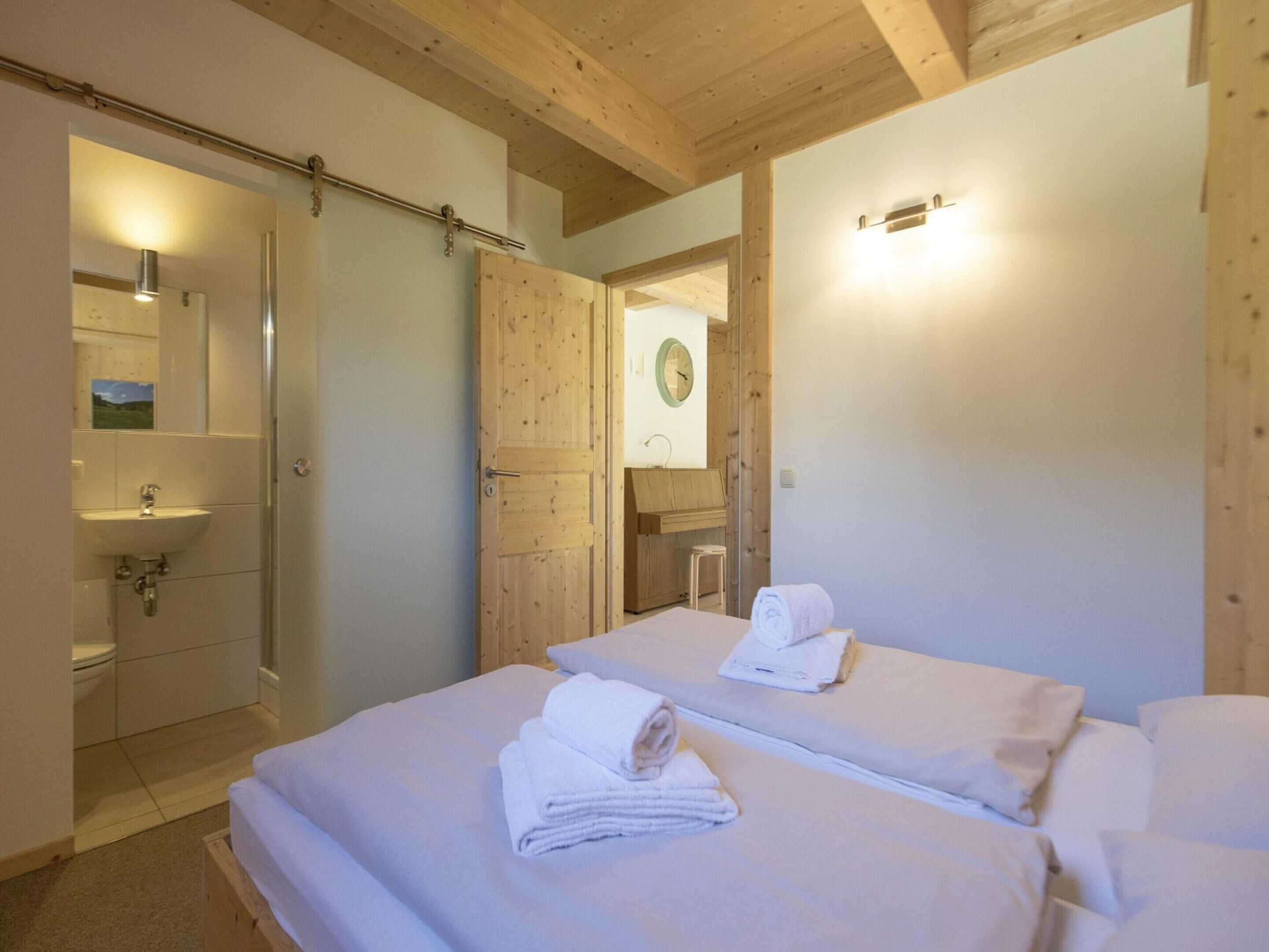 Een hotelkamer met twee bedden, een badkamer met een wastafel en een houten plafond.
