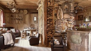 Ein rustikales Blockhaus-Interieur mit Steinwand, Holzmöbeln und Geweih-Dekorationen.