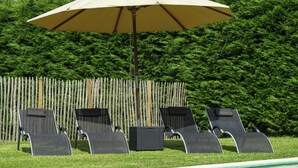 A poolside area with four lounge chairs and a large umbrella.