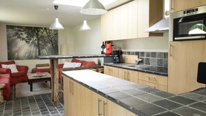 A modern kitchen with a stone countertop, wooden cabinets, and pendant lighting.